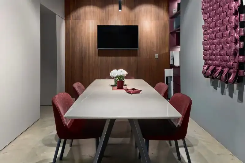 The meeting table at the European Kitchen Center showroom, set with a centrepiece, in front of a walnut feature wall